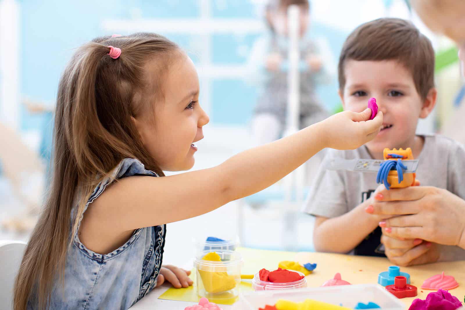 Two small children playing with play dough.