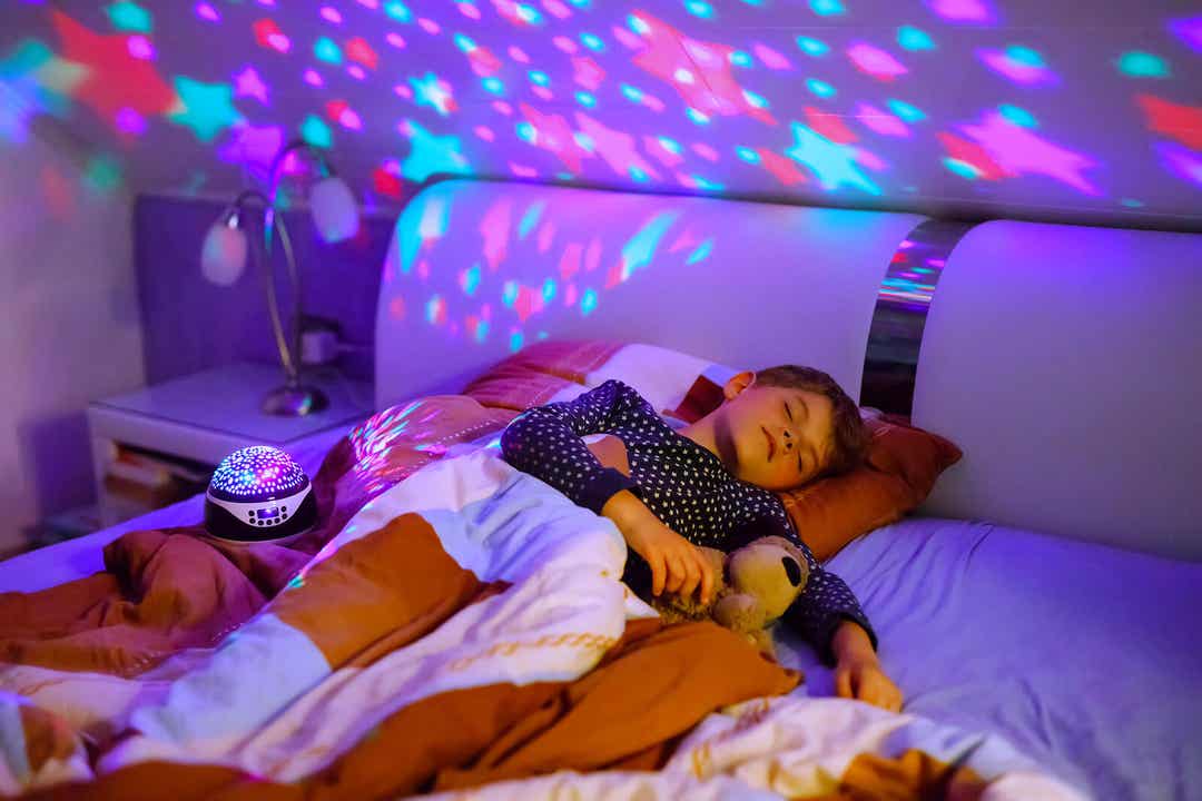 Dziecko śpiące obok projektora gwiazd.