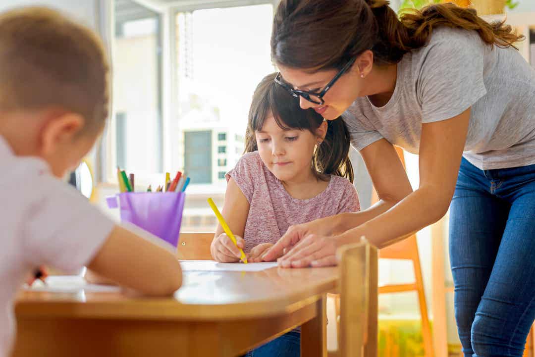 A mother helping her children with their schoolwork at the table.