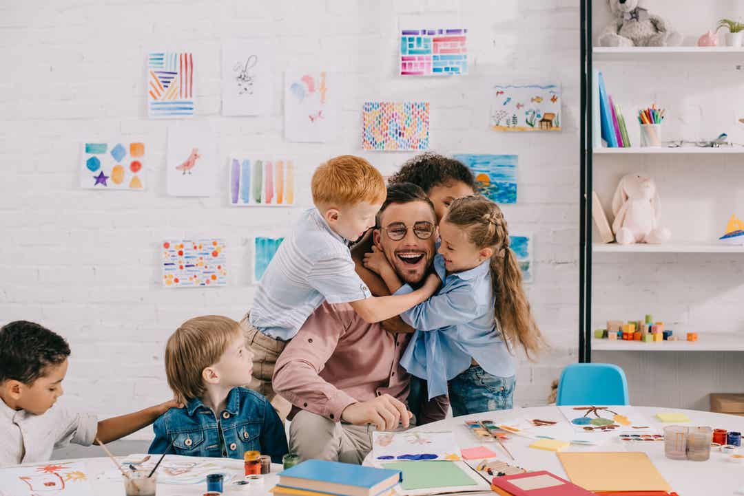 Elementary students hugging their teacher.