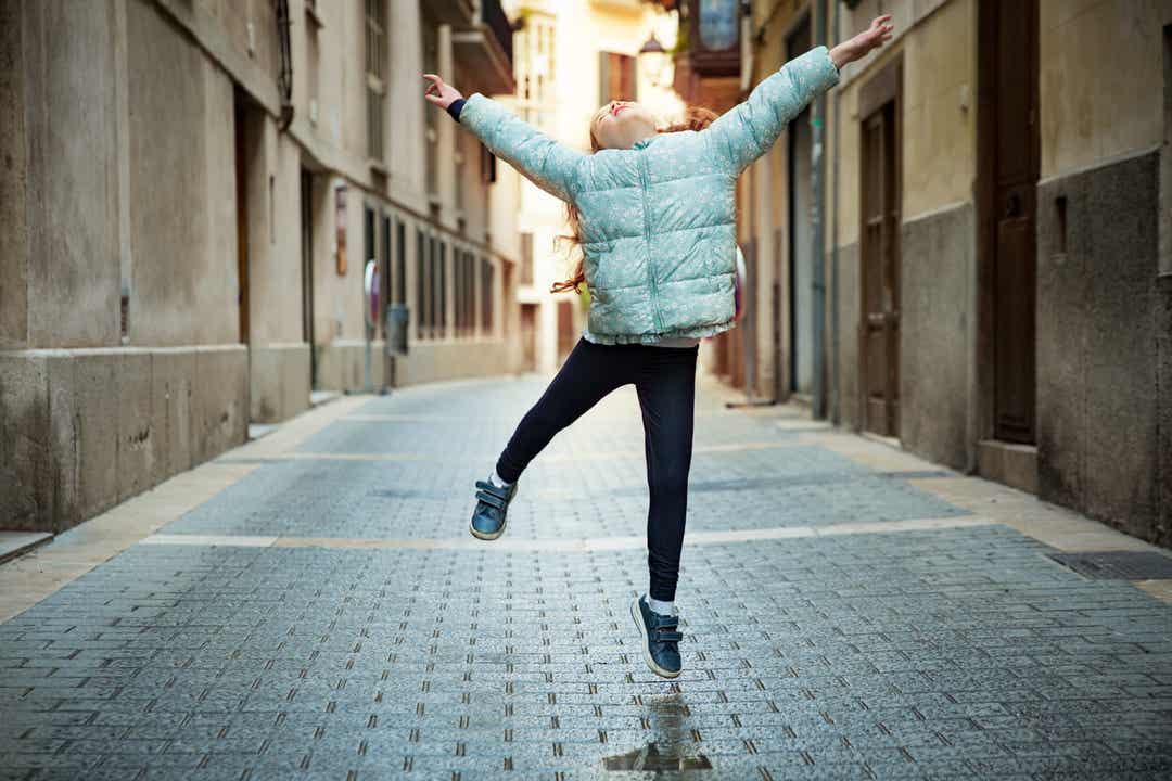 Et barn danser i en smal bygade