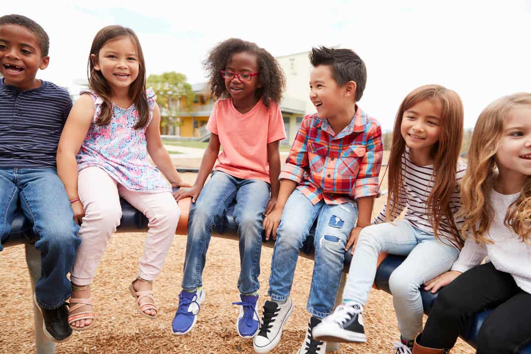 A diverse group of children sitting on playground equipment.