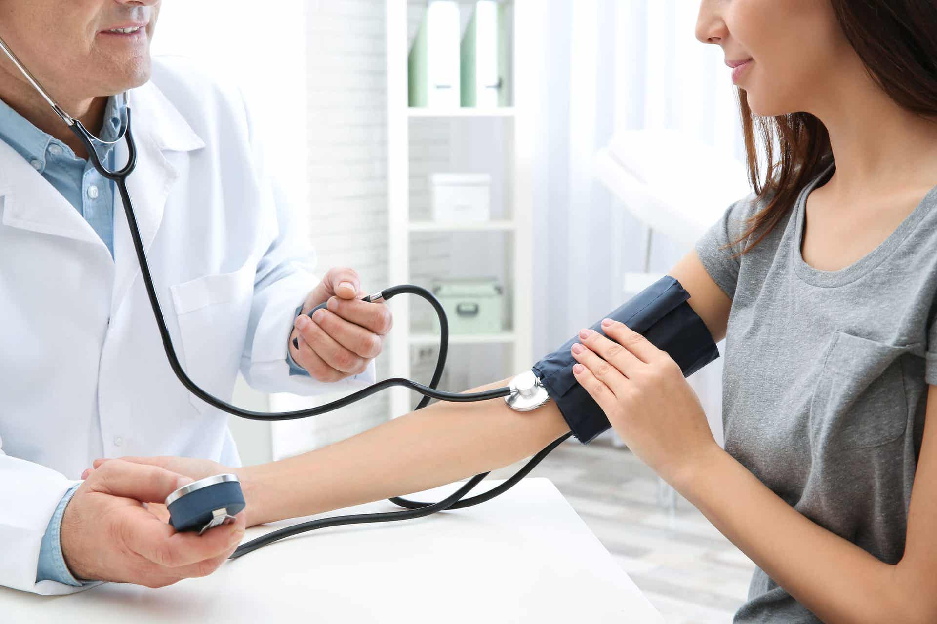 Een arts die de bloeddruk van een vrouw meet.
