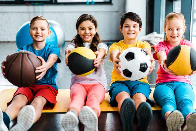 Kids holding different balls.