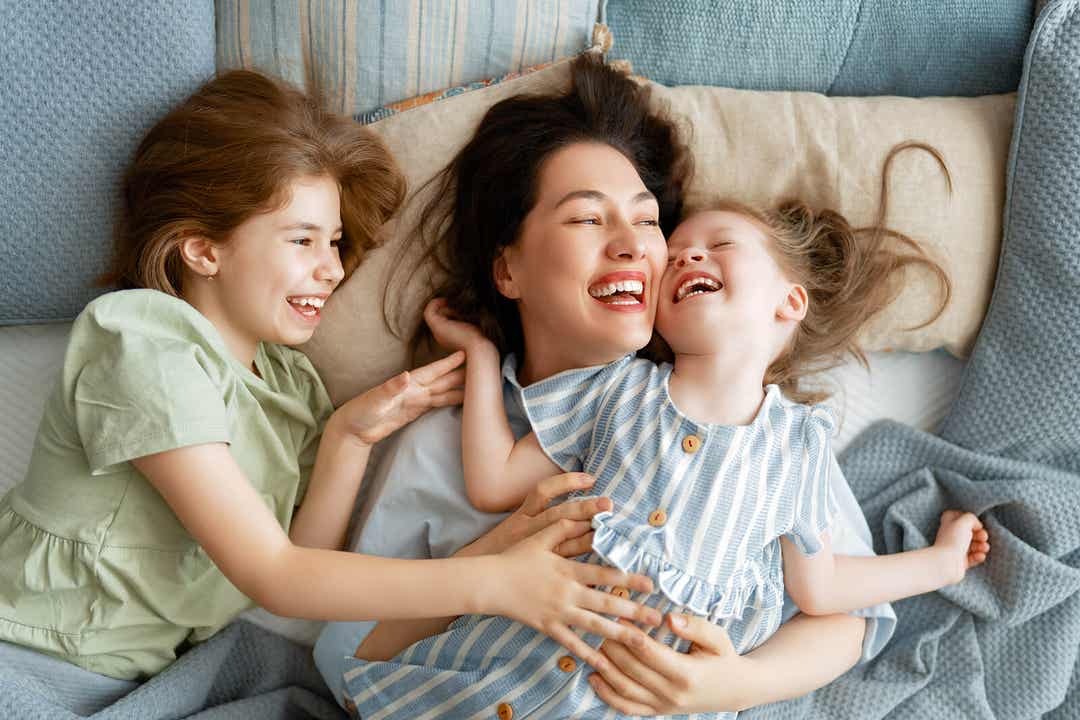 A mother snuggling in bed with her two young daughters.