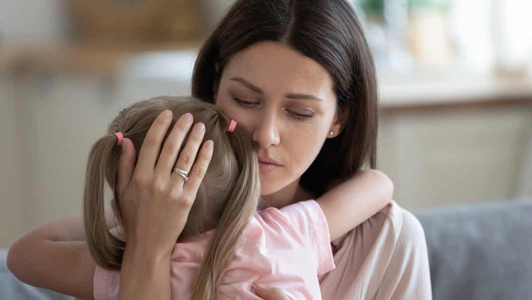 An unhappy mother hugging her little girl.