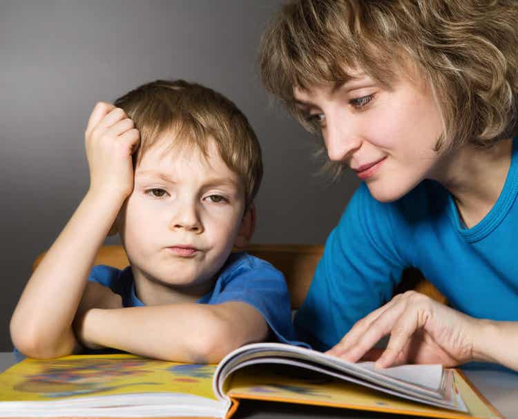 A mother trying to read with her child, who's bored.