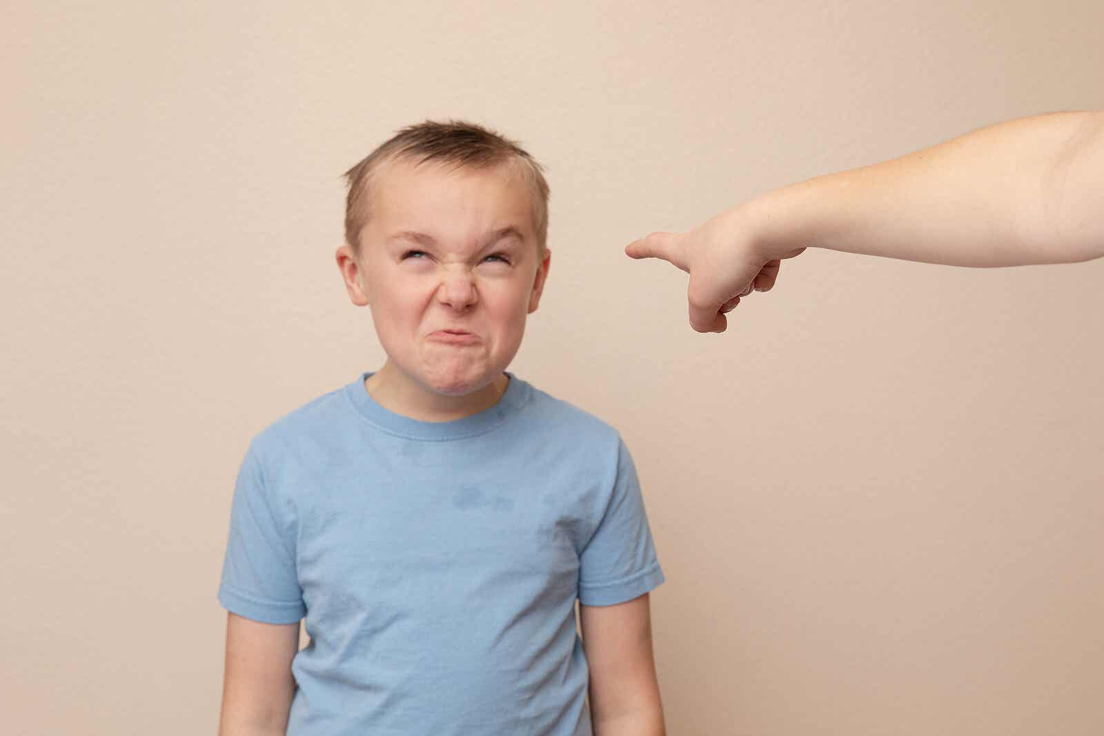 A parent pointing at a child that's making an angry face.
