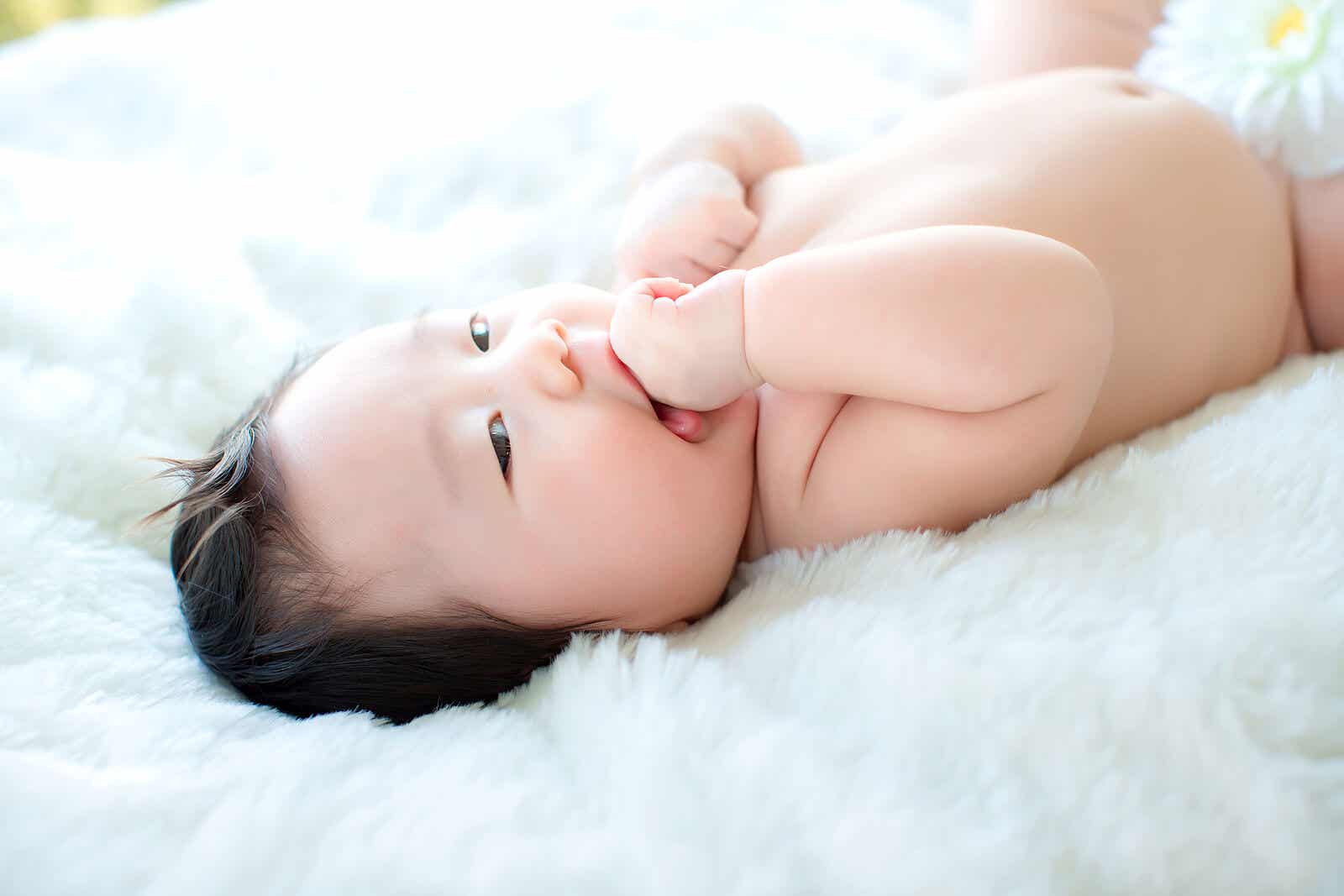 En baby som ligger på et uklart hvitt teppe.