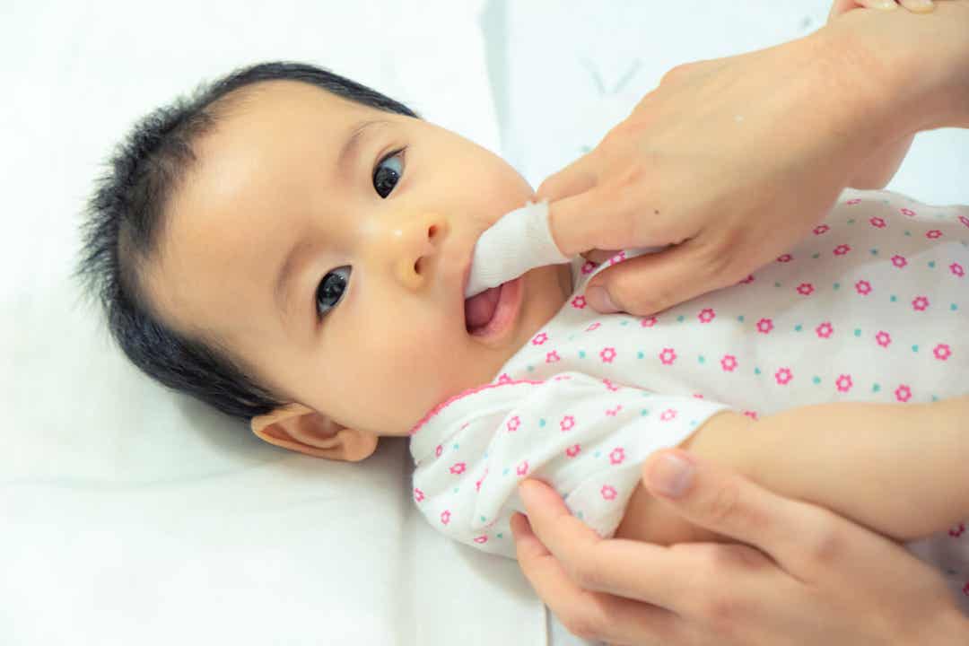 A mother brushing her baby's gums.
