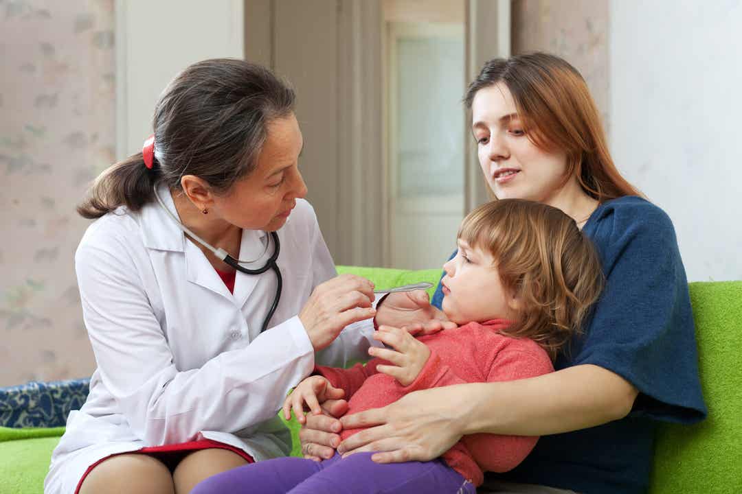 A mother sitting with her toddler son on her desk during a pediatric visit.