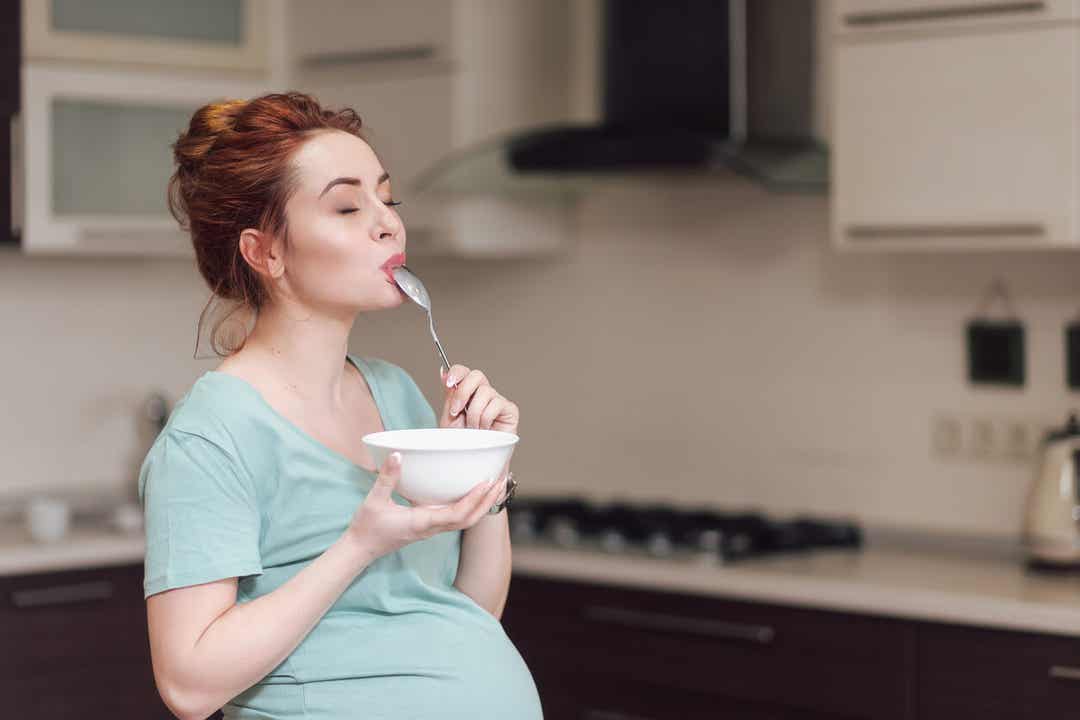 A pregnant woman enjoying a bowl of yogurt.