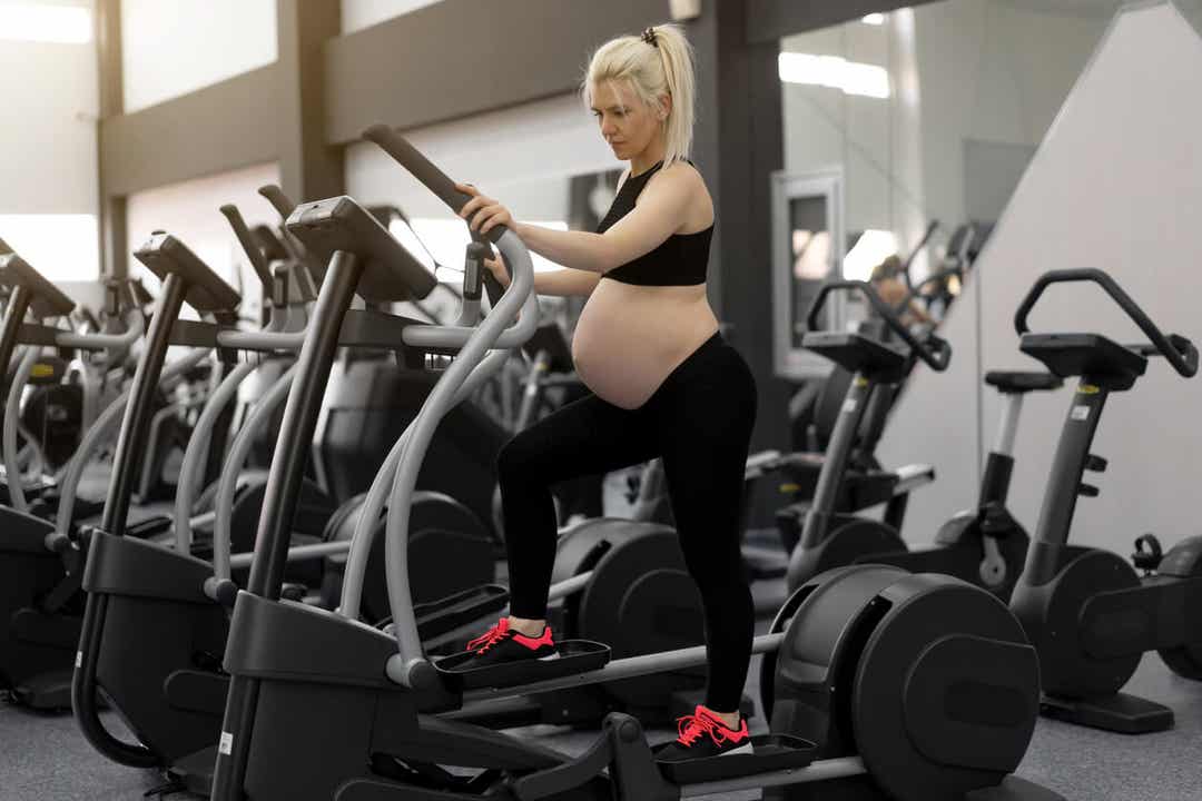En gravid kvinde på en crosstrainer