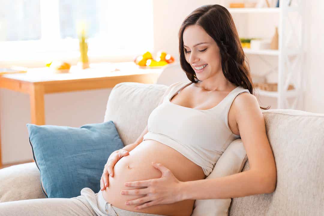 A pregnant woman with her hands on her bare belly.