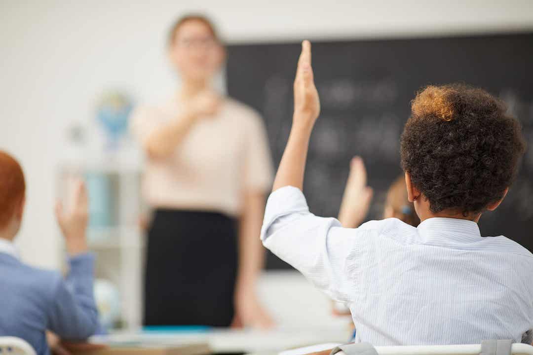 En pojke räcker upp handen i ett klassrum.