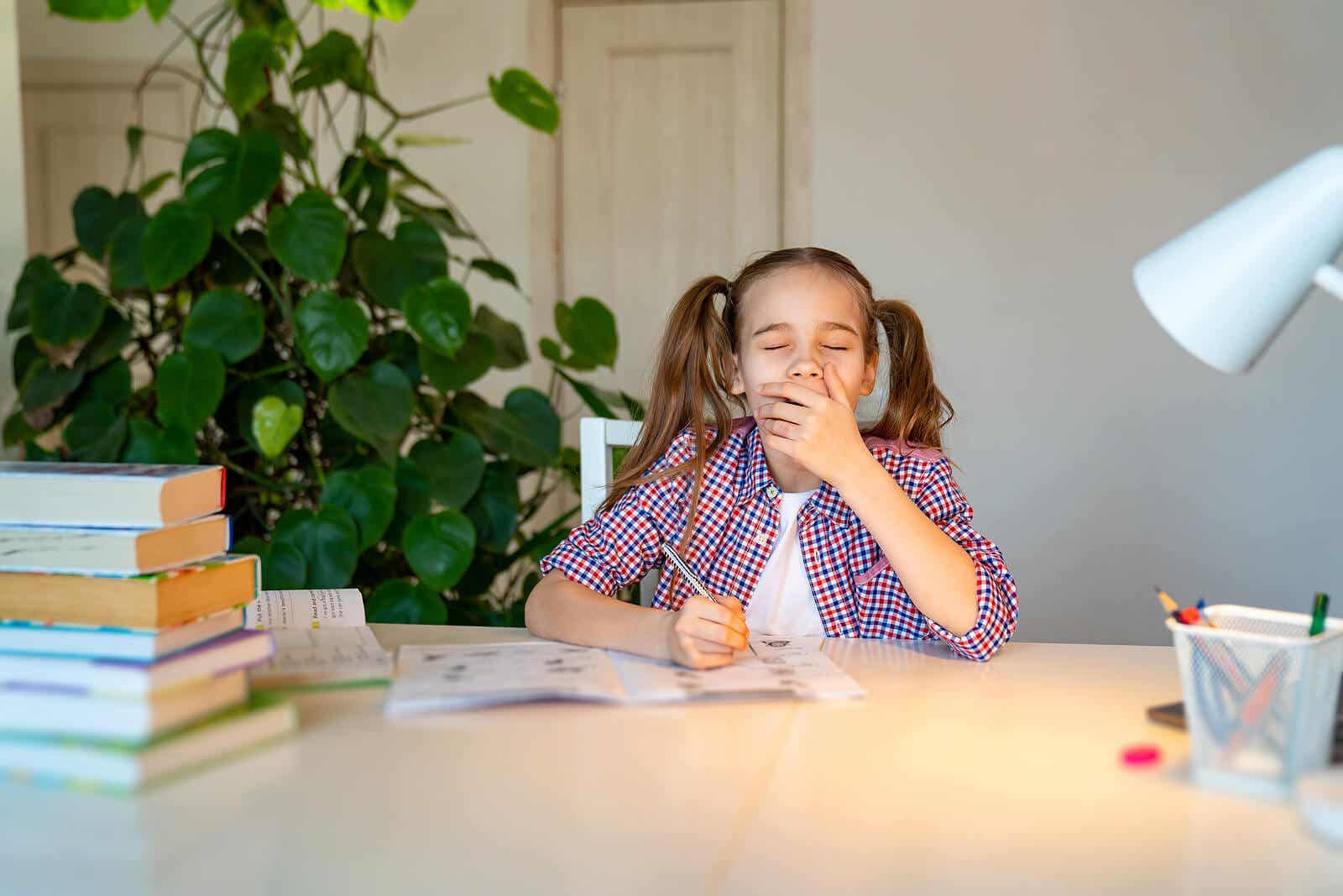 A teenage girl yawning while she does her homework.