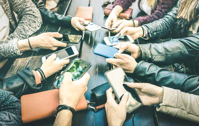 Tonåringar sitter med sina telefoner.