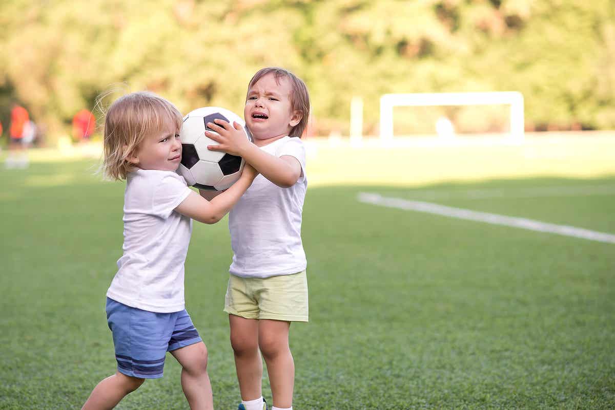 Two kids fighting over a soccer ball.