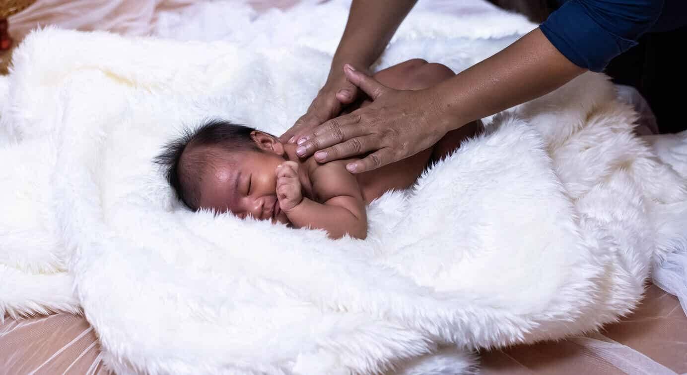 Mother massaging her newborn baby.