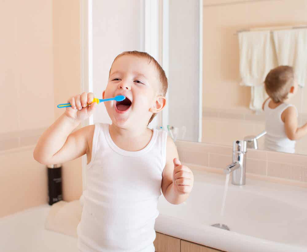A toddler boy brushing his teeth and smiling.