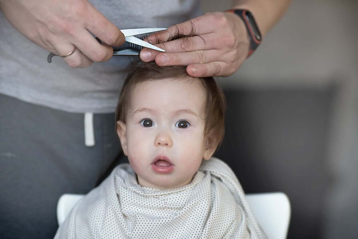 A father cutting his baby boy's hair.