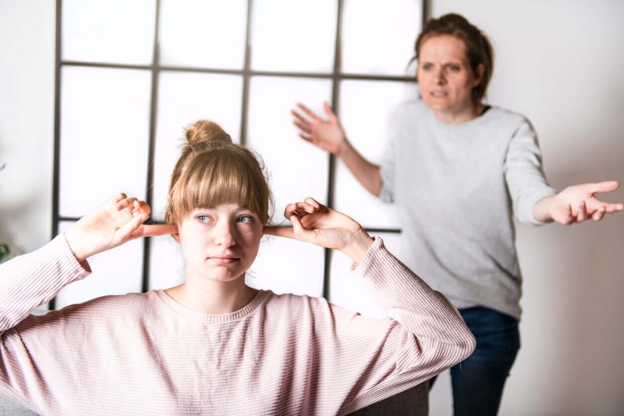 En tenåringsjente tetter ørene mens moren roper på henne.