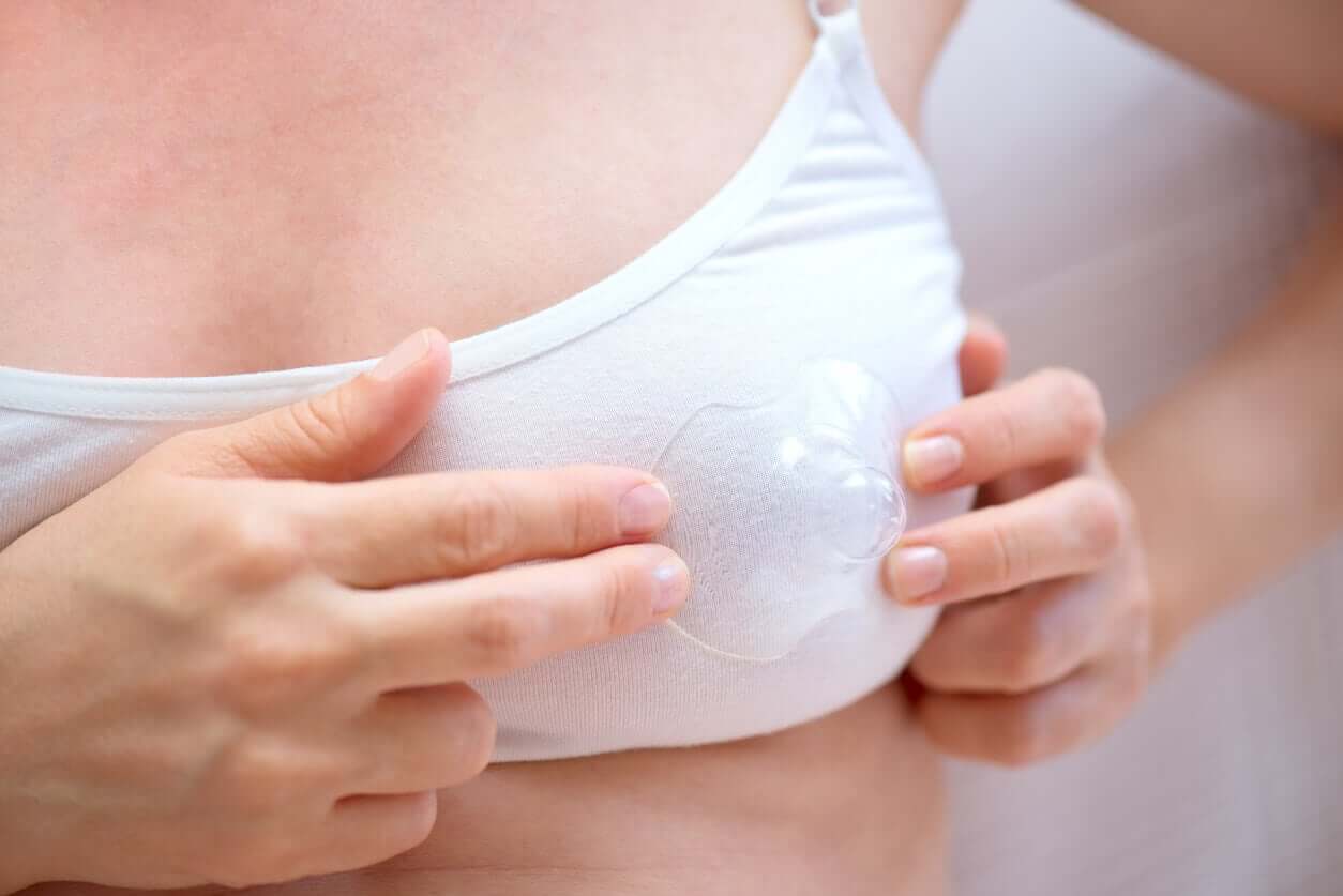 A woman holding a nipple shield over her bra.