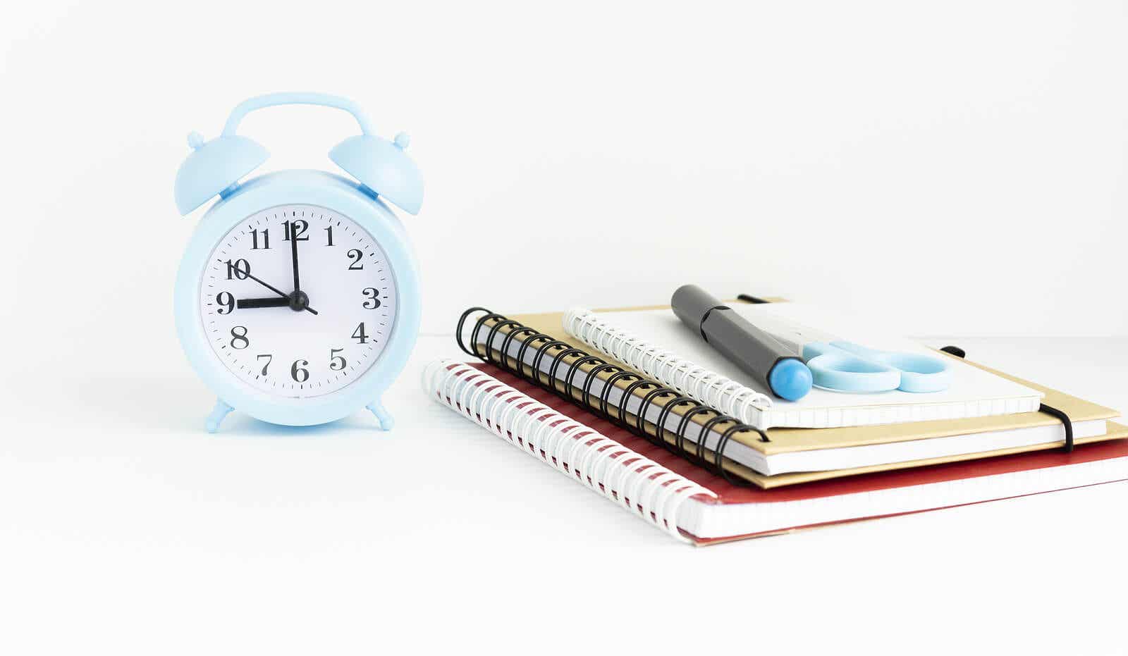 An alarm clock, notebooks, a pen, and scissors.