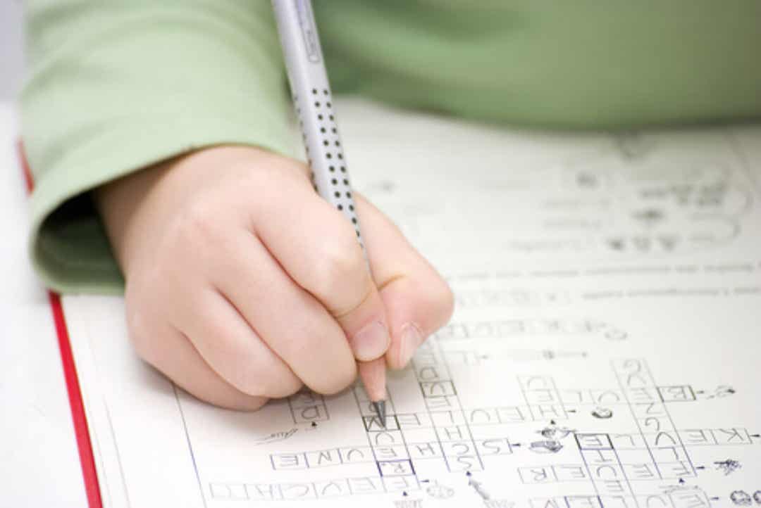 A young child working on a crossword puzzle.