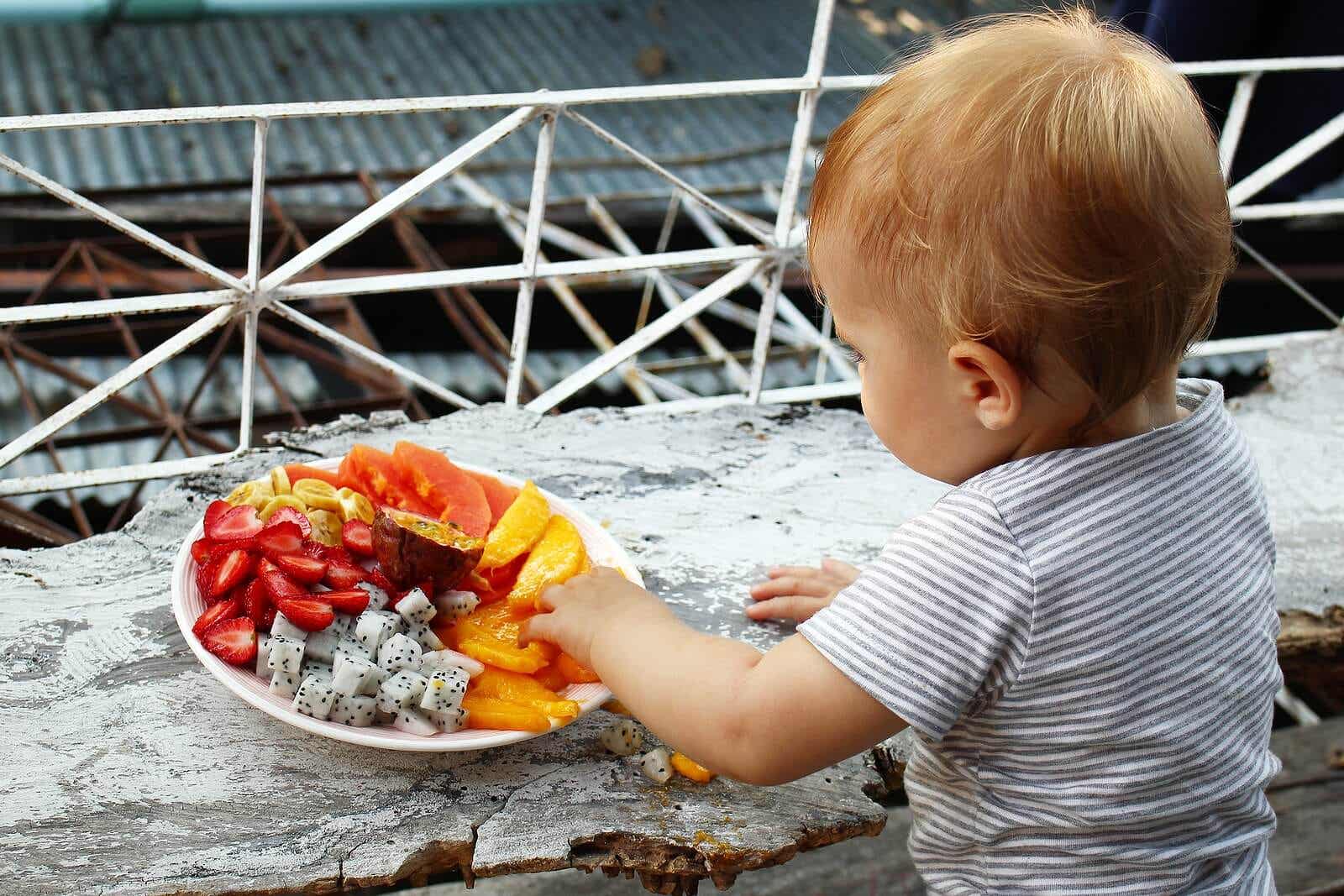 A baby eating fresh fruit.