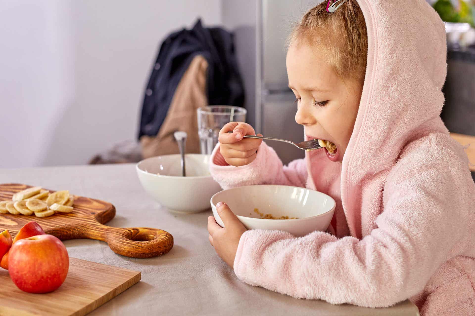 A young girl eating oatmeal at the table.