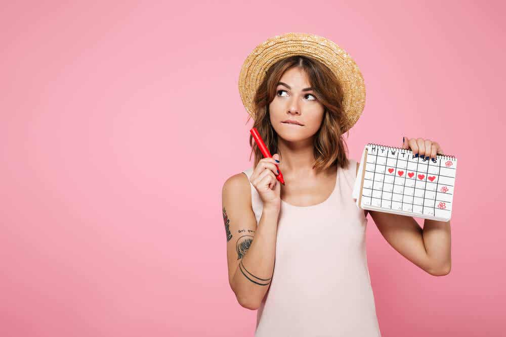 En kvinna som håller en kalender med dagarna under hennes menstruation markerad på den.