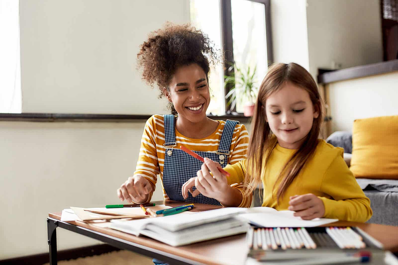 Een moeder die met haar jonge dochter kleurt