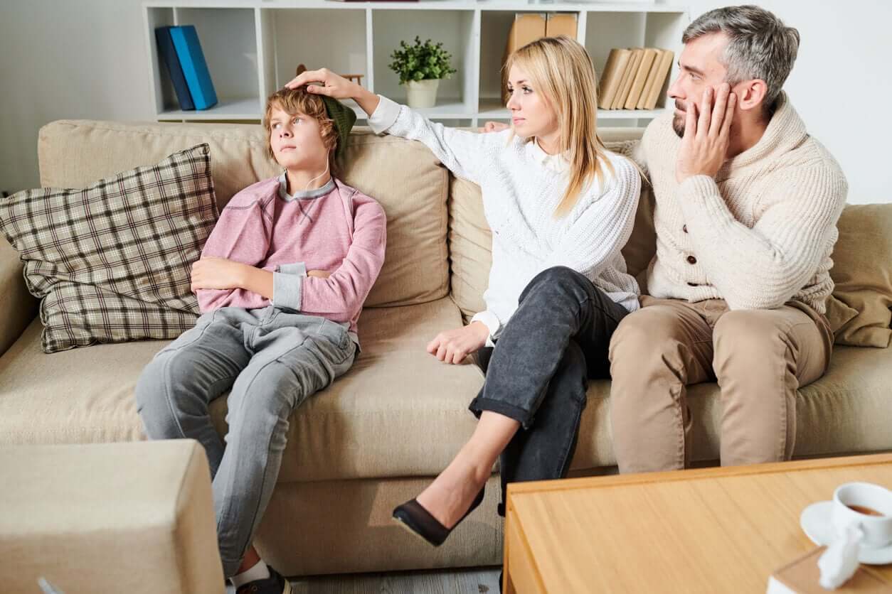 Föräldrar med sin tonåriga son i soffan.