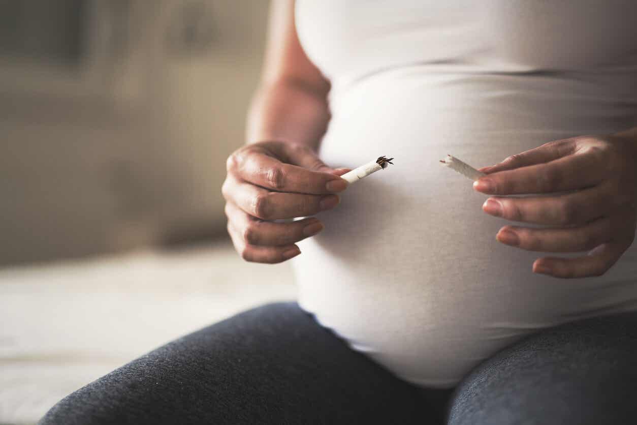 A pregnant woman breaking a cigarette in half.