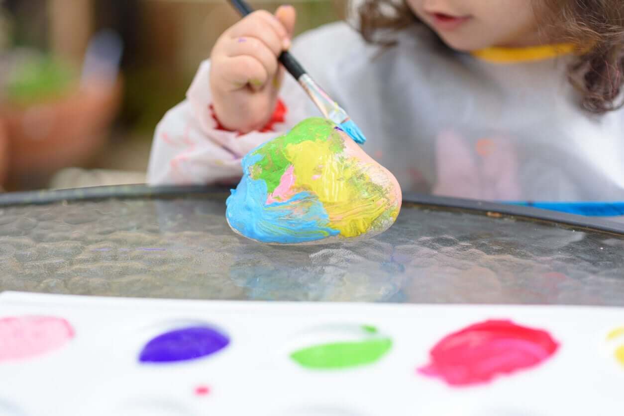 A toddler painting a stone.