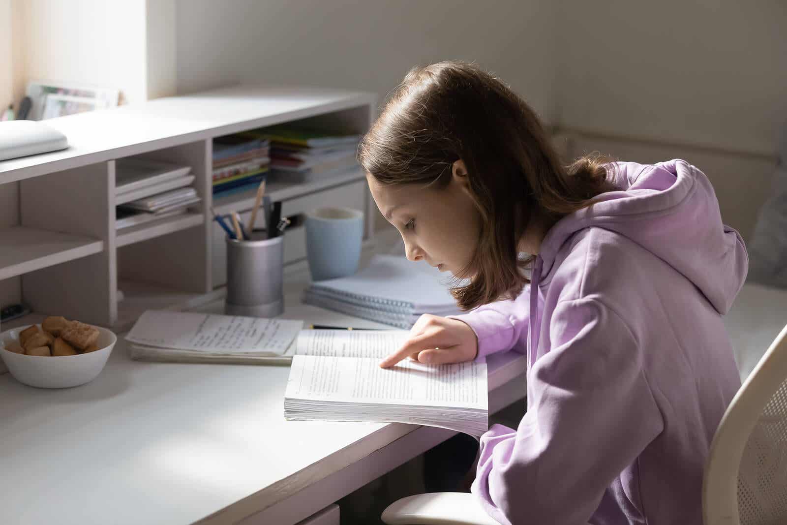 An adolescent girl studying at her desk in her room.