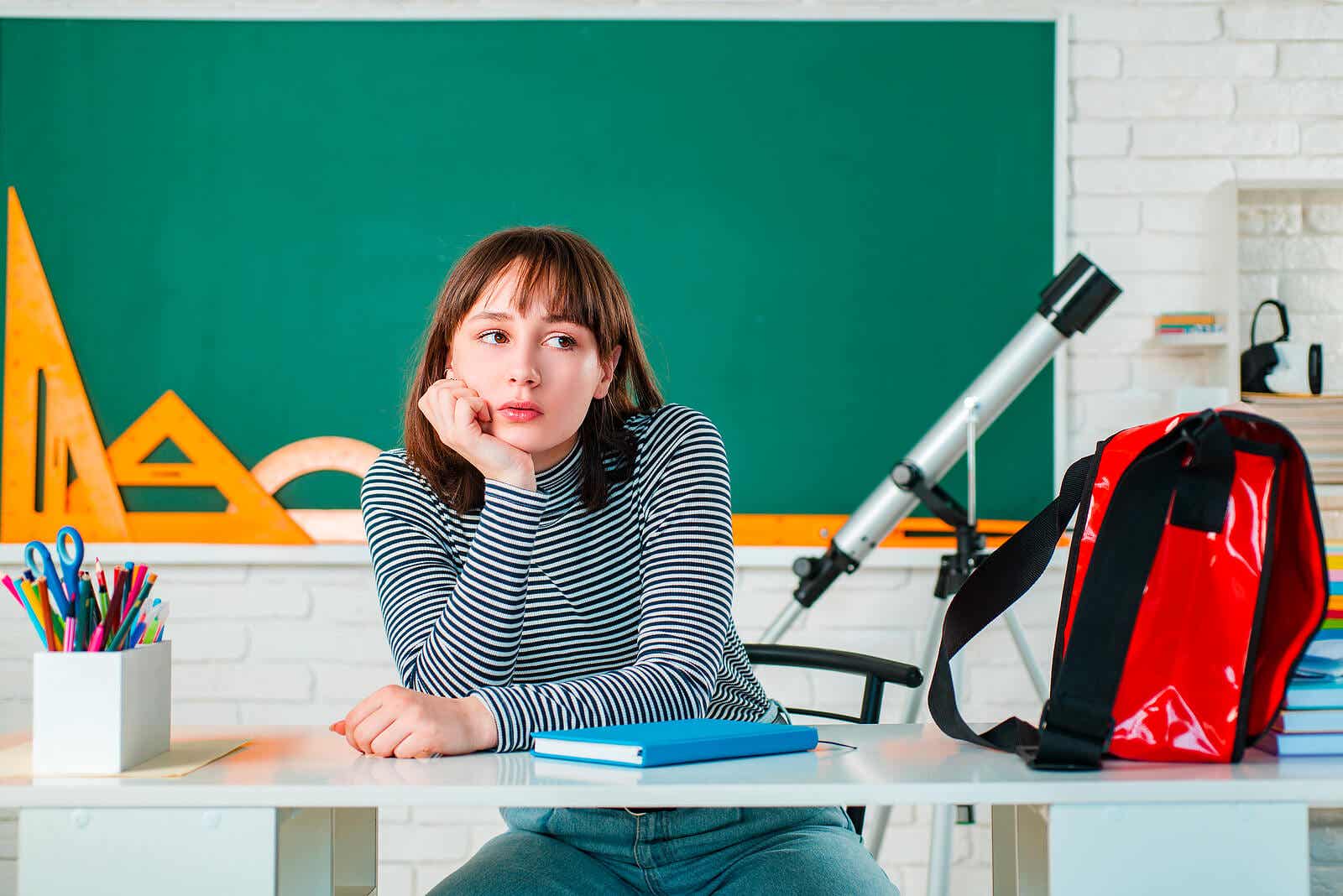 A teenager sitting in a classroom thinking.