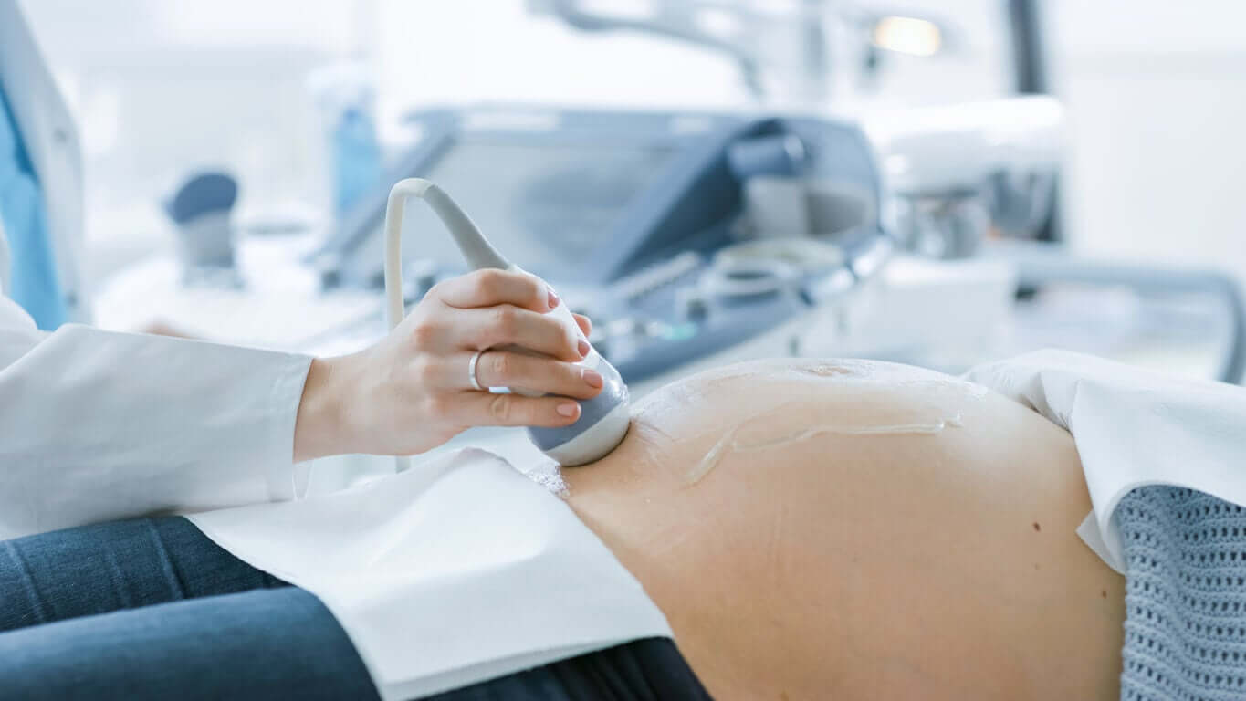 A doctor performing an ultrasound on a woman's pregnant belly.
