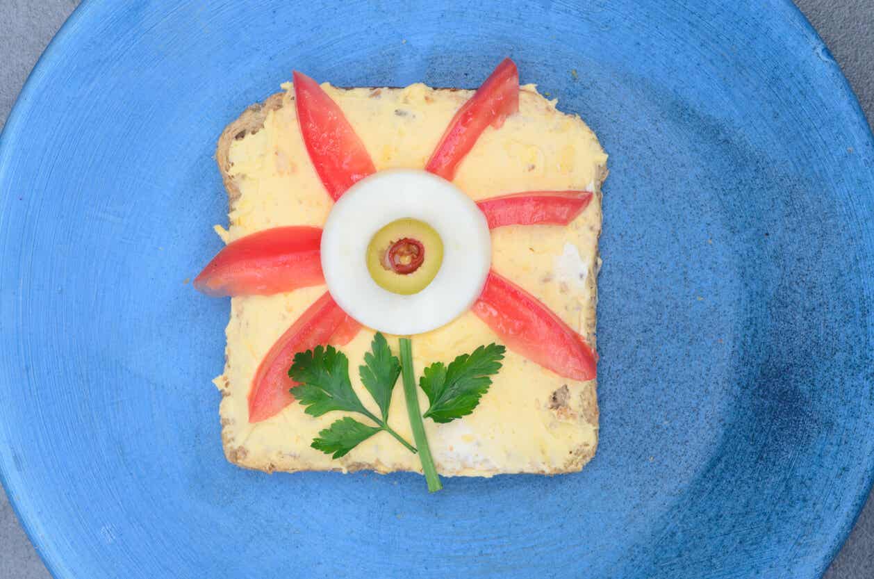 A egg sandwich with tomato wedges and an egg slice forming the shape of a flower.