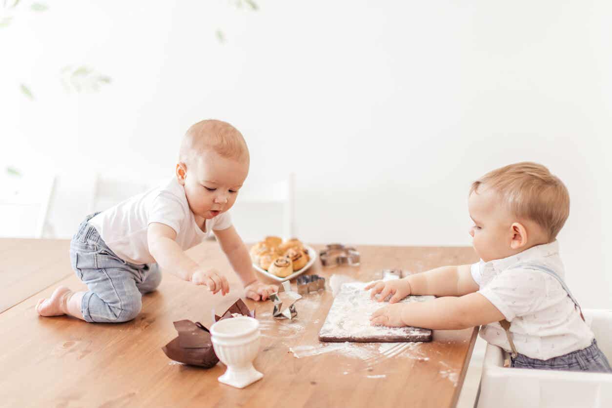 Two babies playing with flour and pastries.