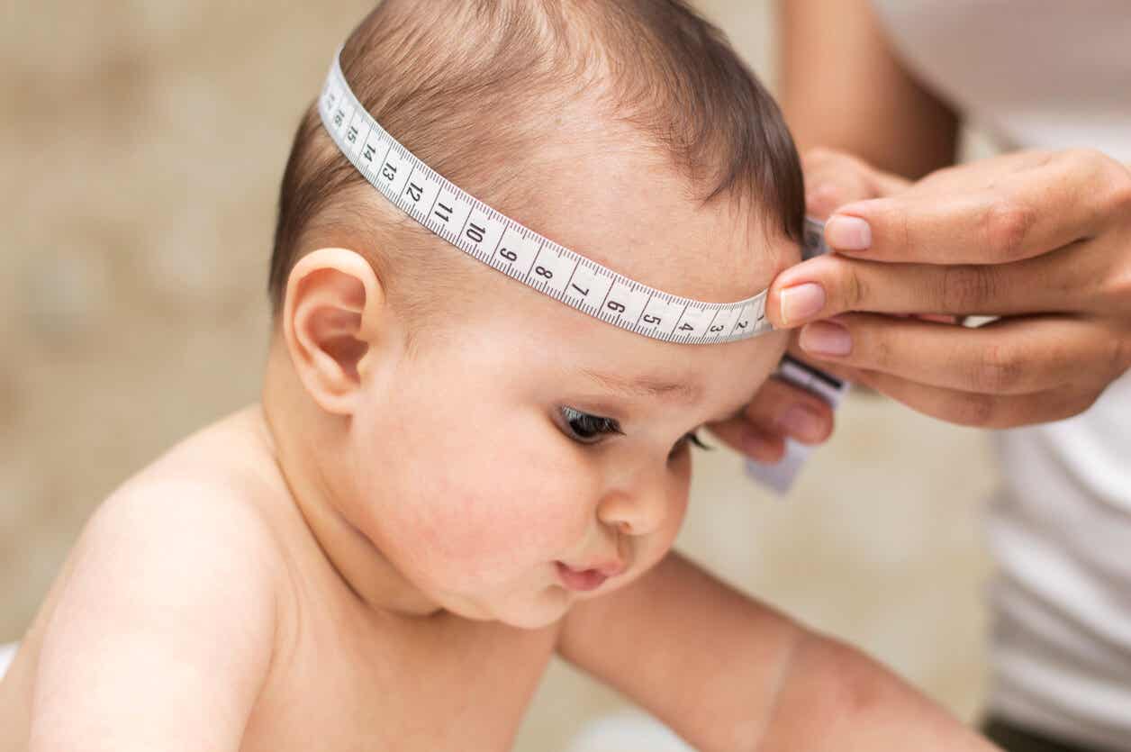 Een arts die het hoofd van een baby meet.