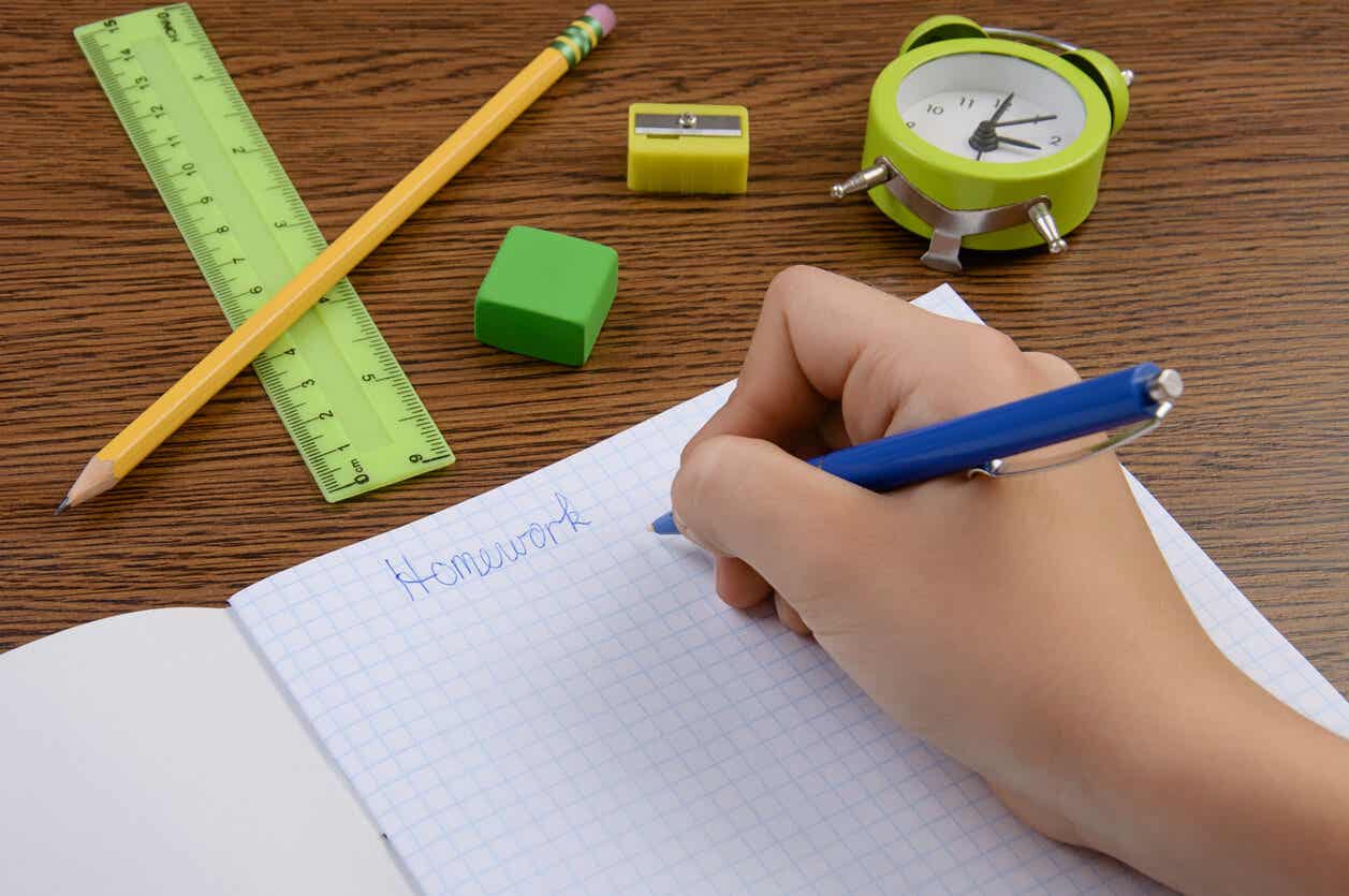A child writing in their school notebook with an alarm clock nearby.