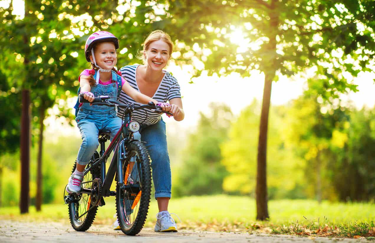 A mother teaching her daughter to ride a bike.