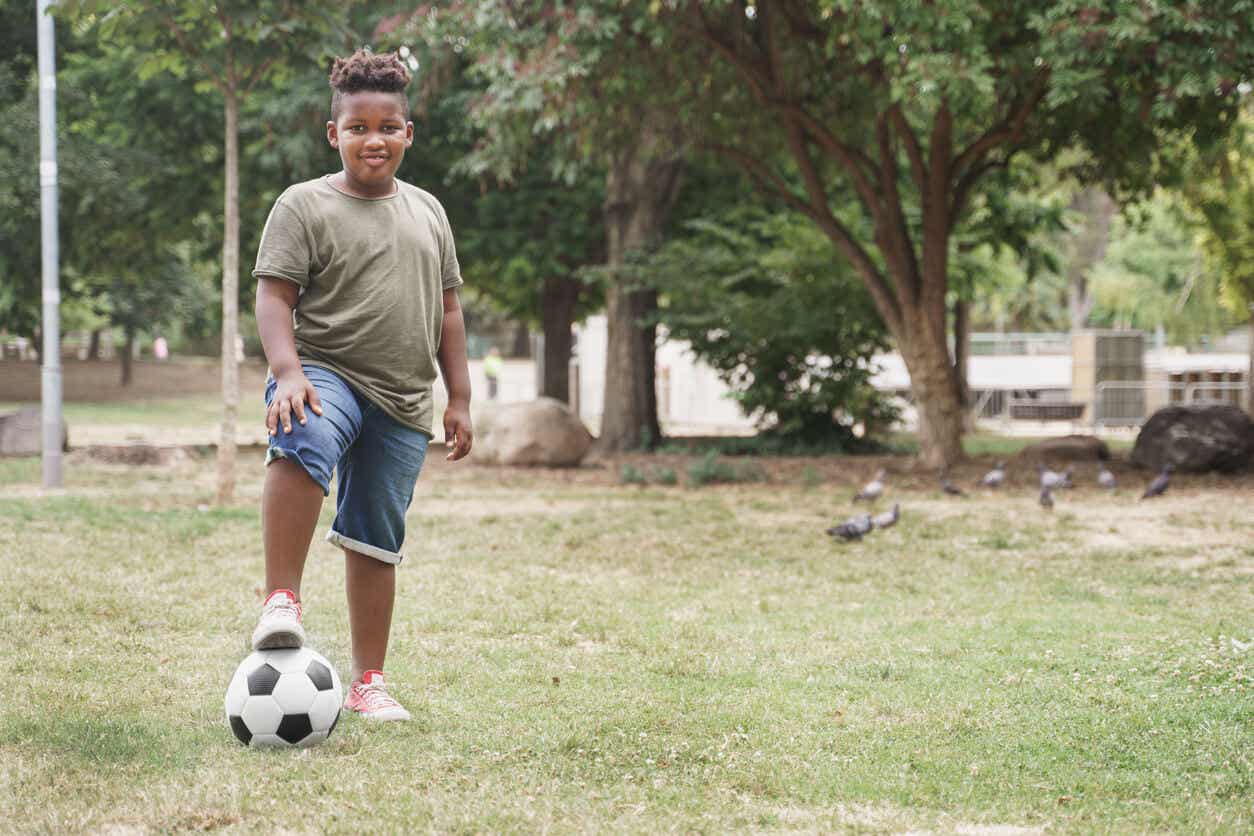 An overweight child playing soccer.