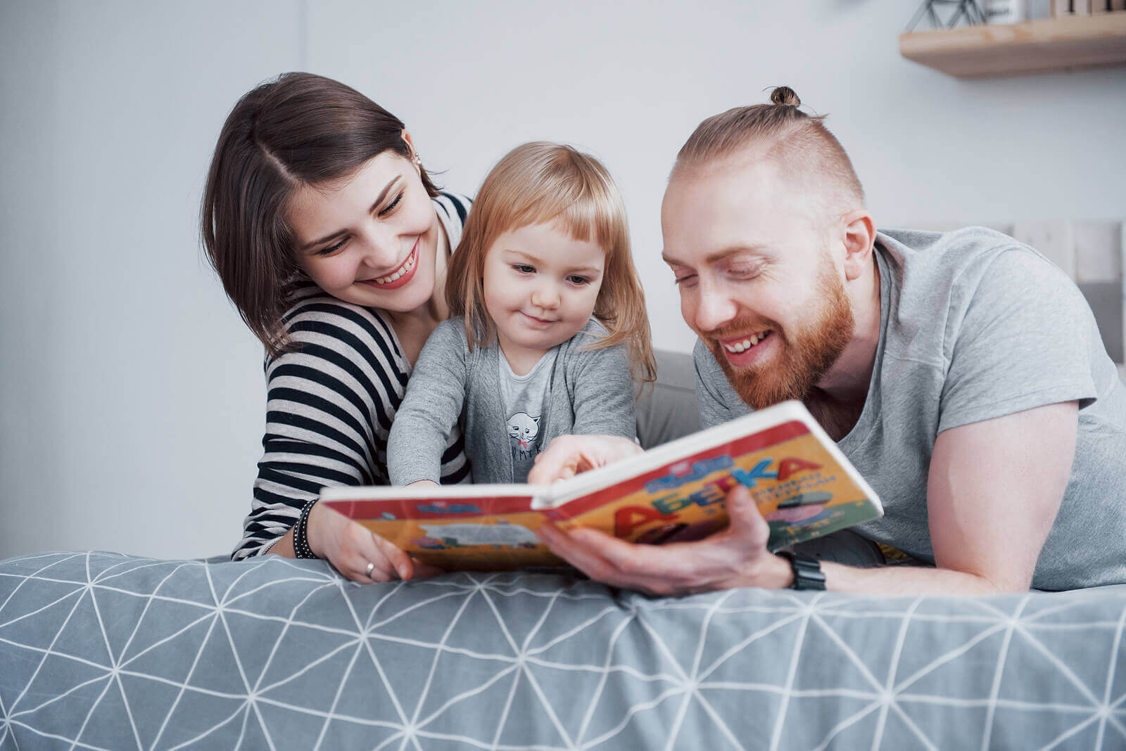 Parents reading a book to their toddler.