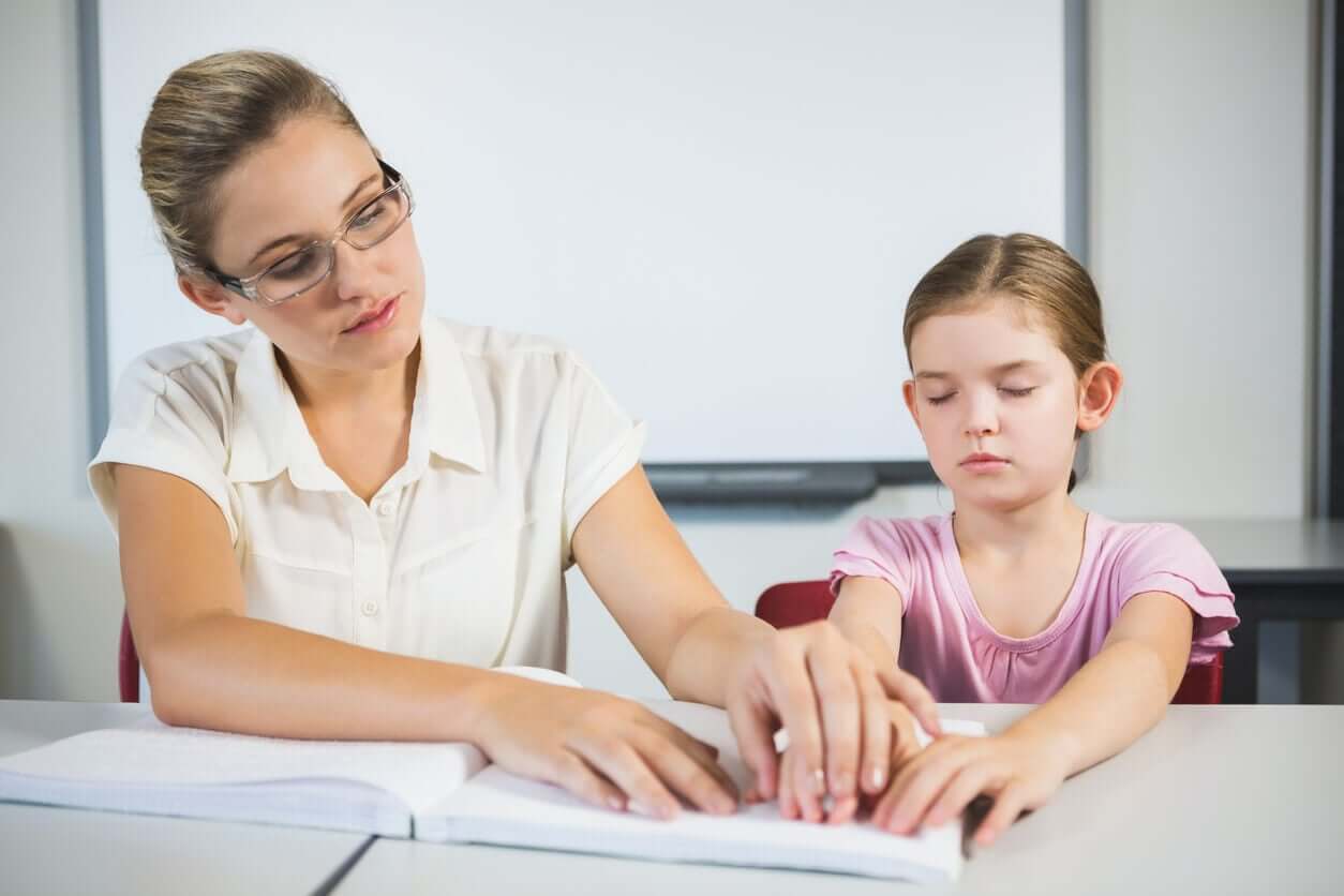 A teacher helping a young girl read braille.