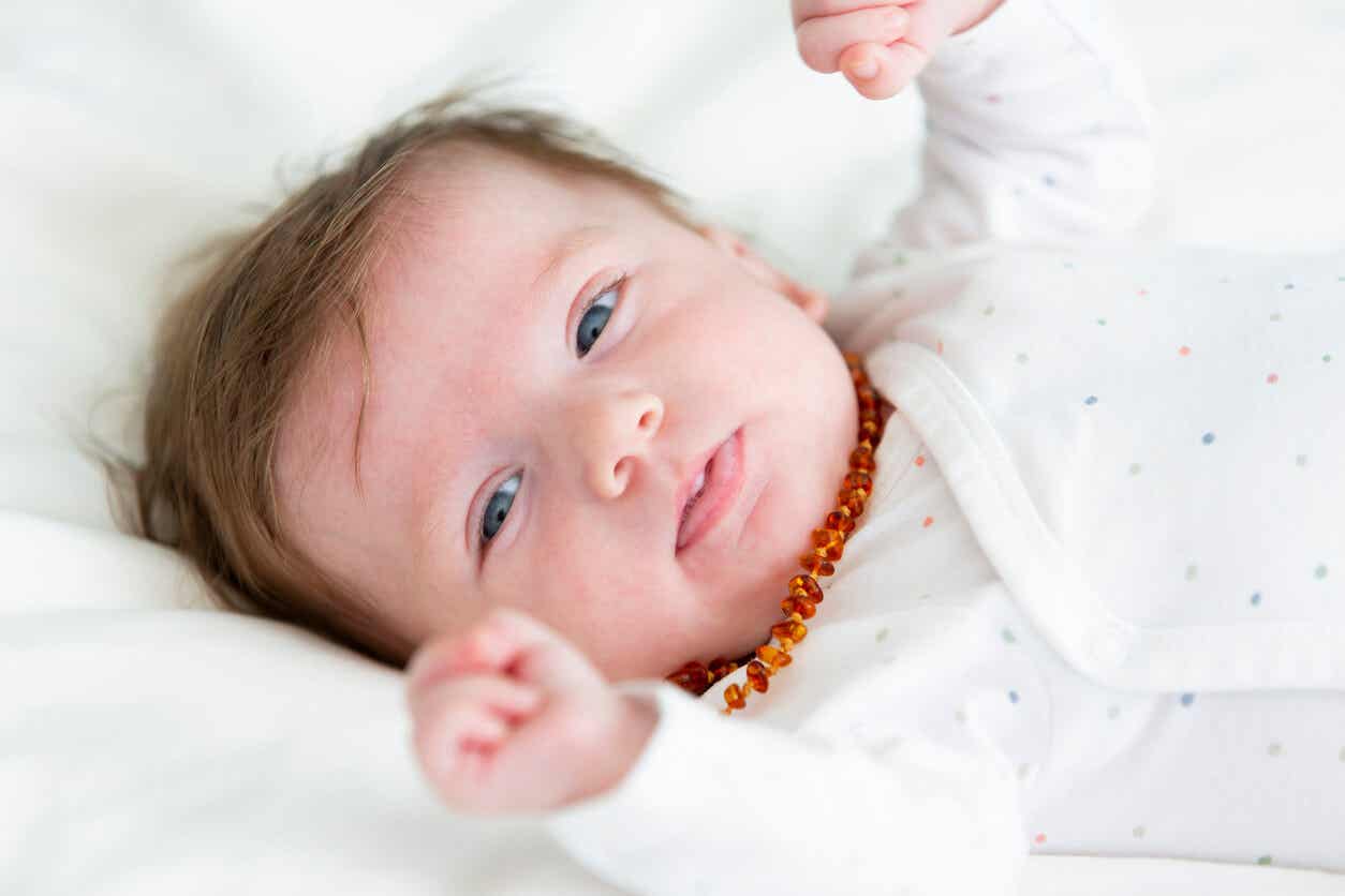 A newborn with an amber necklace around her neck.