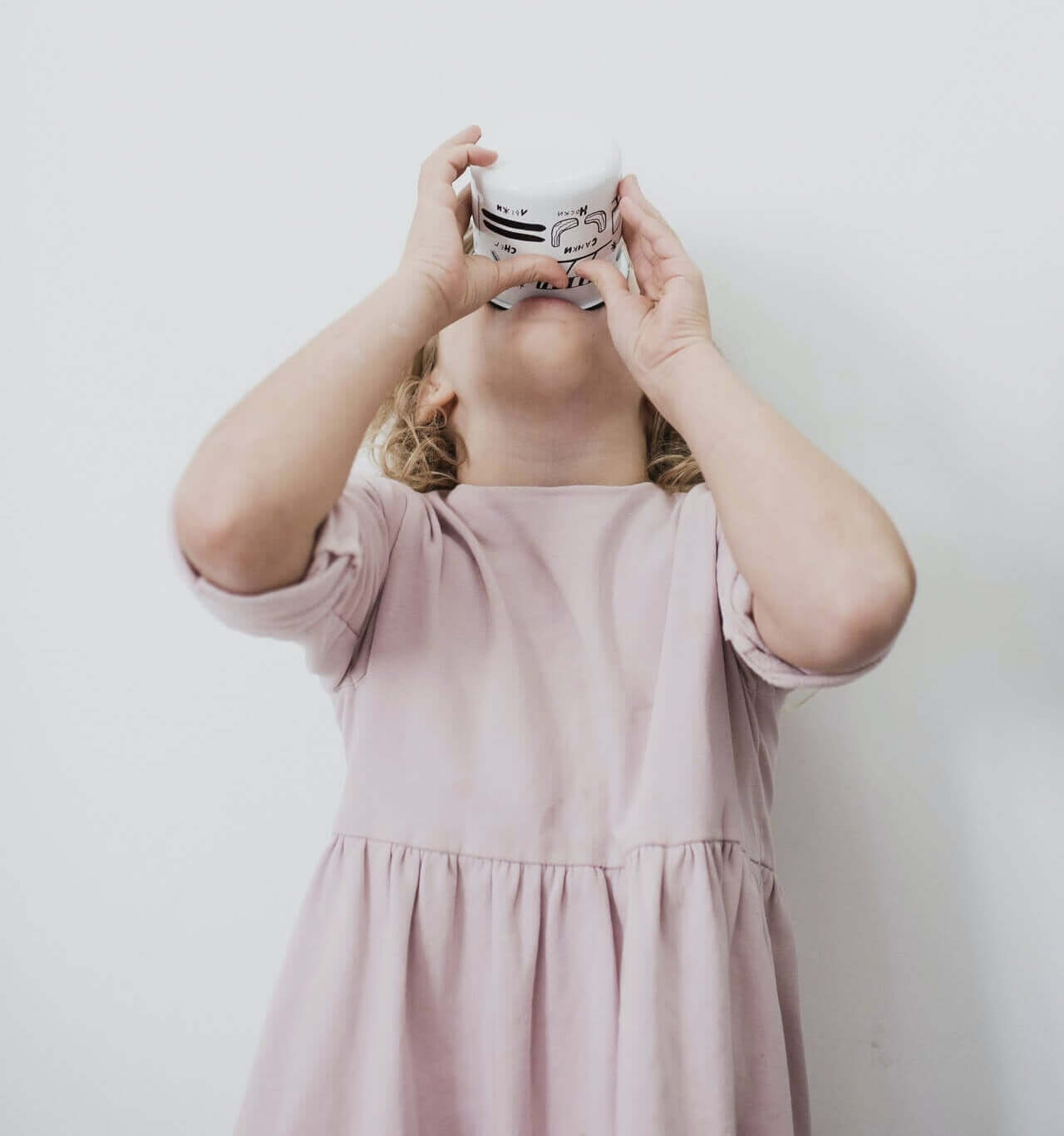 A young girl drinking yogurt.