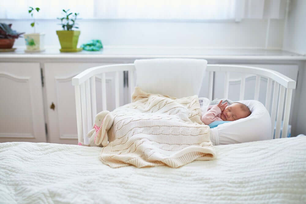 Baby slaapt in bedje dichtbij de moeder